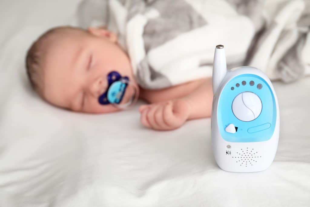 Baby monitor and sleeping child on bed. Radio nanny