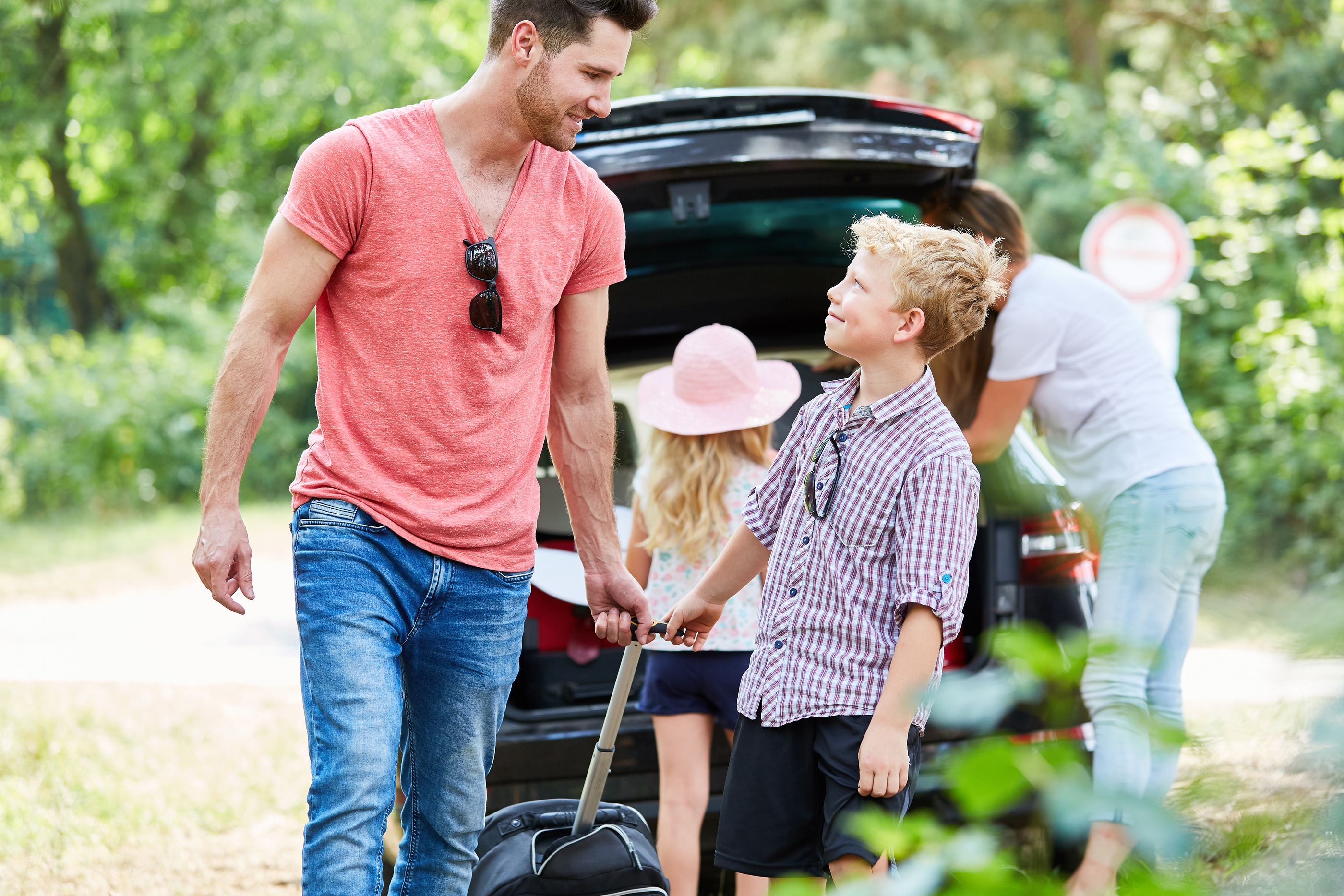 Son helps father carry luggage before traveling on summer vacati