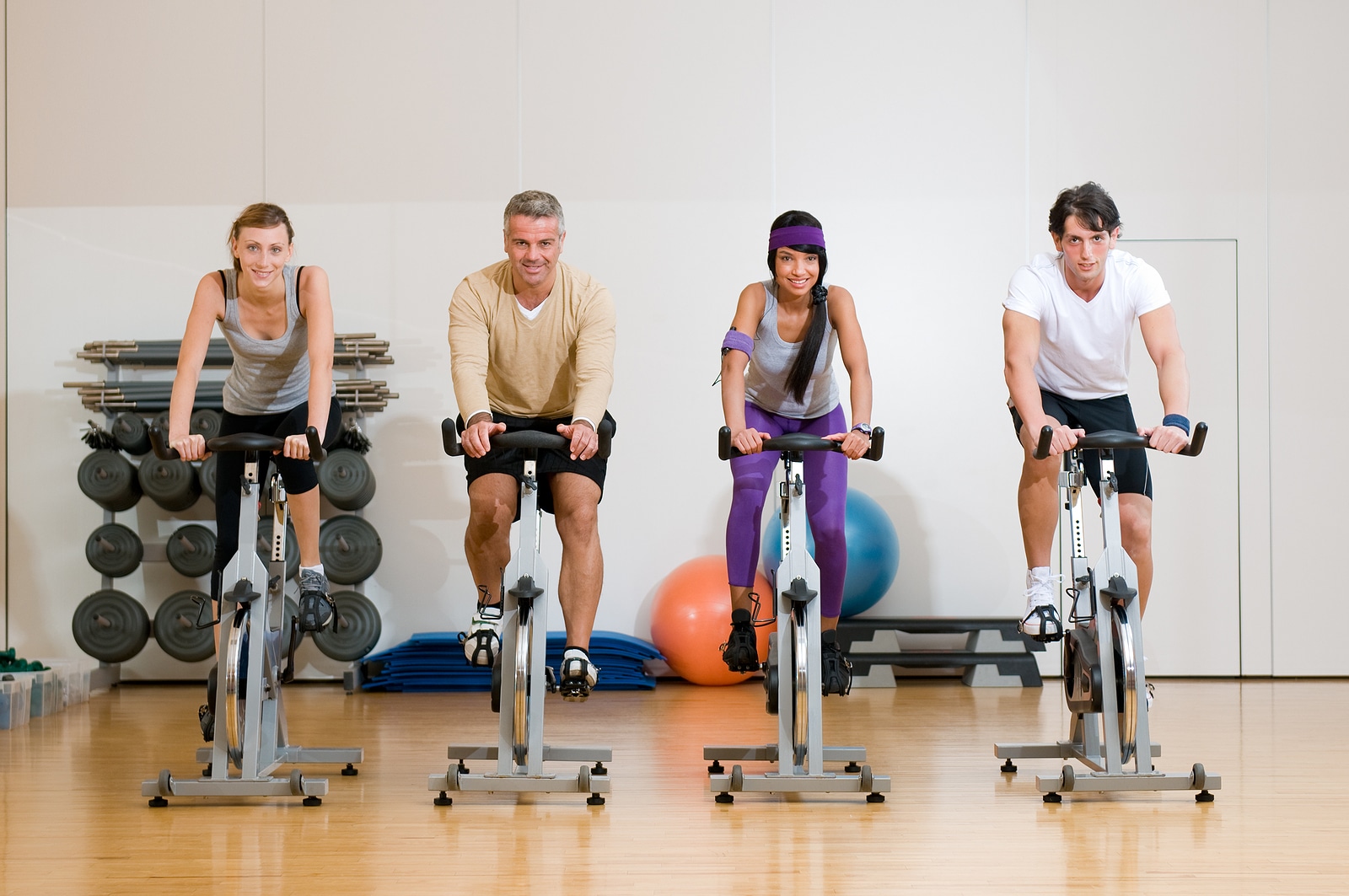Happy active people exercising with bicycles in a gym Front vie
