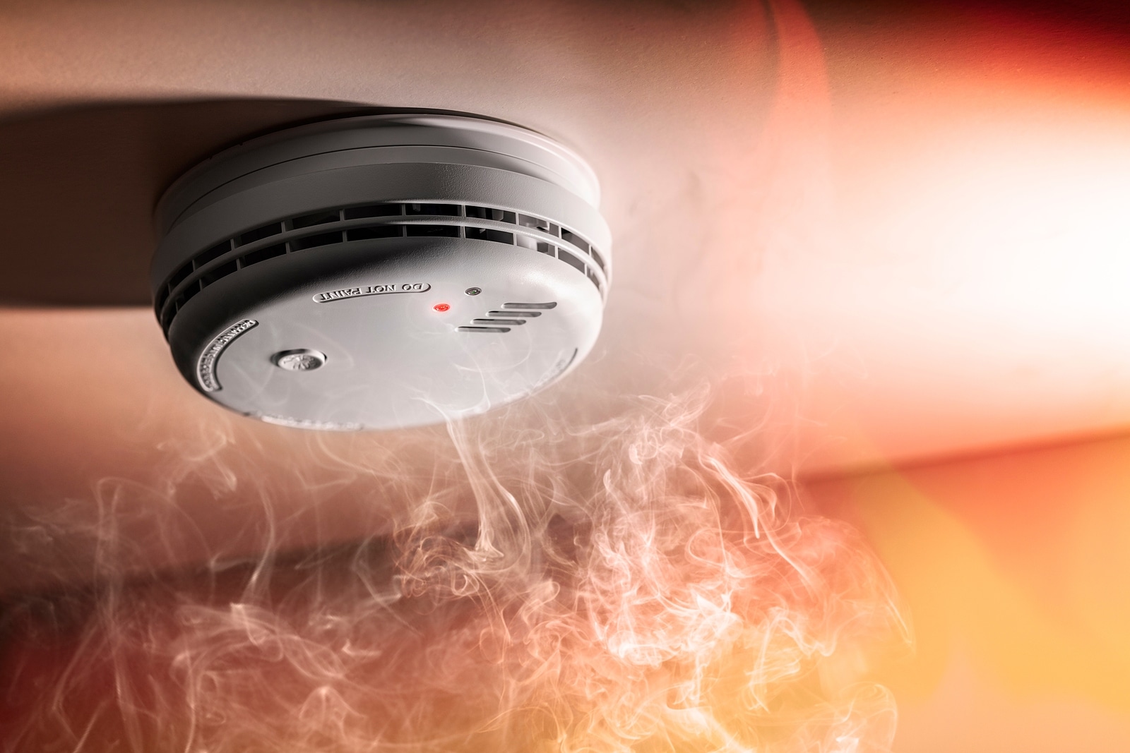 Smoke detector and interlinked fire alarm in action background w