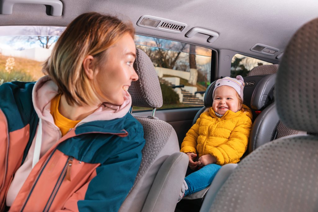 A happy mother and a cute child are sitting in the car.