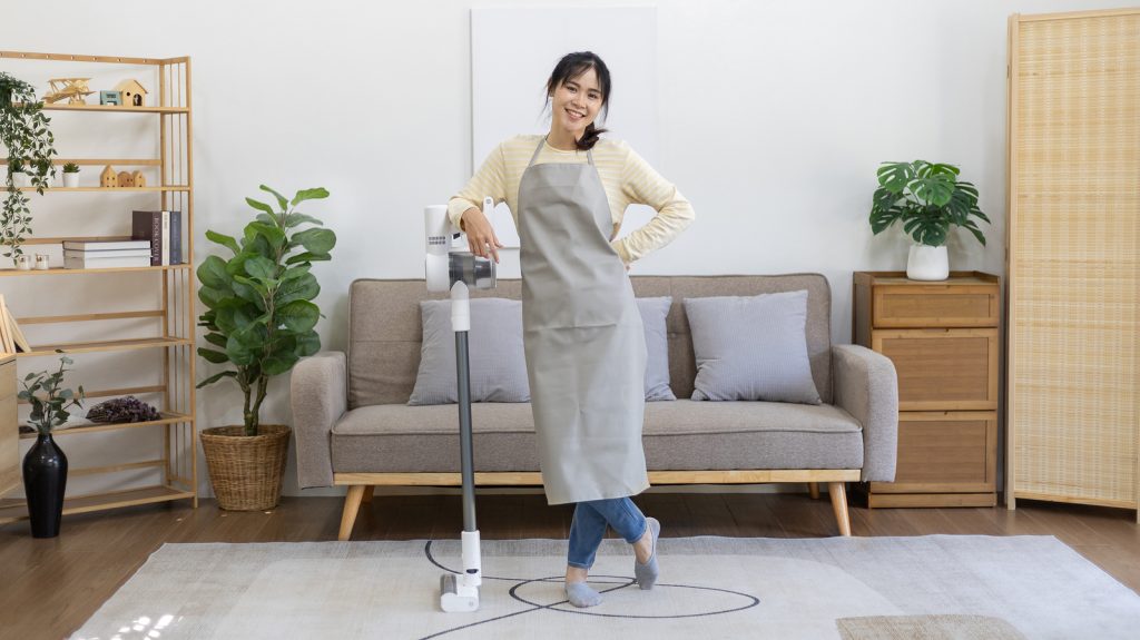 Beautiful housewife standing next to a vacuum cleaner and ready to do a big house cleaning job