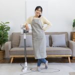 Beautiful housewife standing next to a vacuum cleaner and ready to do a big house cleaning job
