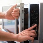 Woman's Hands Closing Microwave Oven Door And Preparing Food in microwave. - Savvy Home Guide
