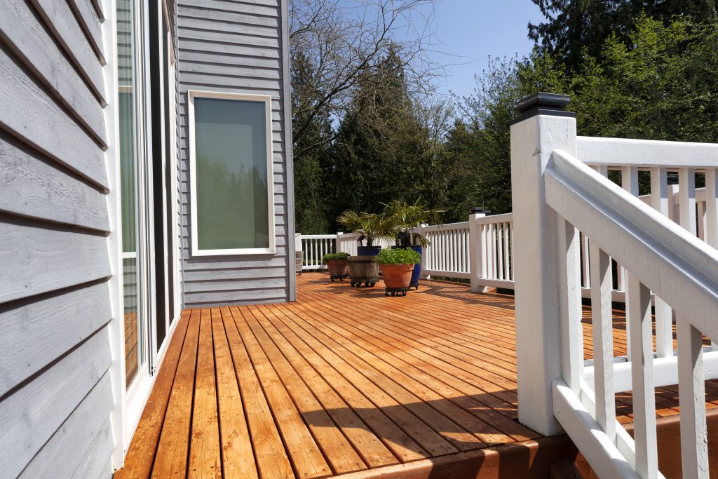 Freshly stained walk out home outdoor cedar wood deck with potted plants in bloom