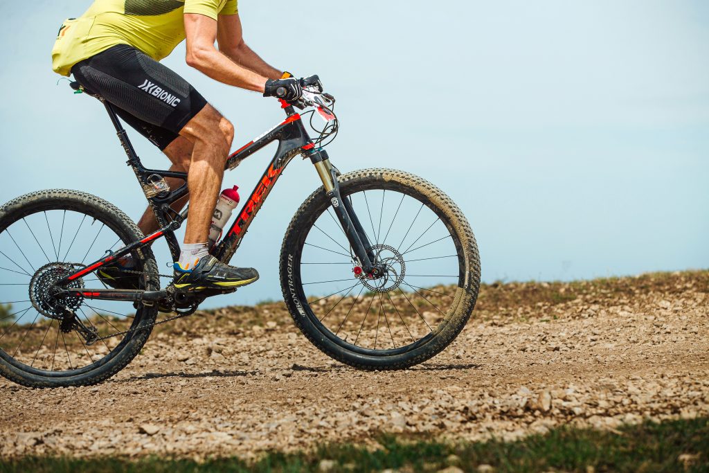 cyclist riding mountain bike uphill cross-country cycling. Trek bikes, Bontrager tires, X-Bionic functional sportswear