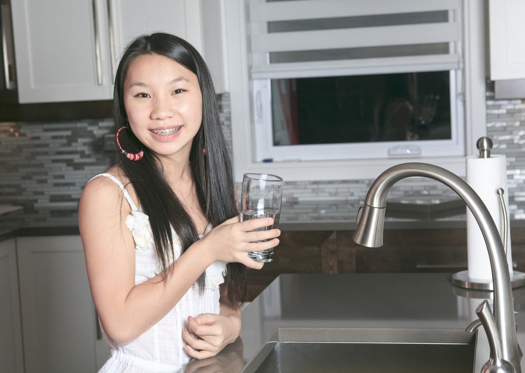teenager girl drinking water in the kitchen