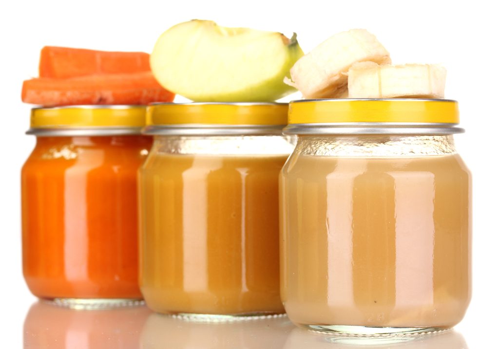 Jars of baby puree with spoon isolated on white 